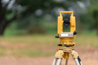 İnşaat makinelerinin arka planına sahip yol veya binanın inşaat sahasındaki Surveyors ekipmanlarının önü (teodolite veya toplam konumlandırma istasyonu)