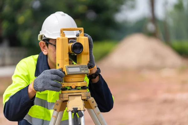 建設現場における設備のセオドライト又はトータルポジショニングステーションを用いた測量士土木技術者 — ストック写真