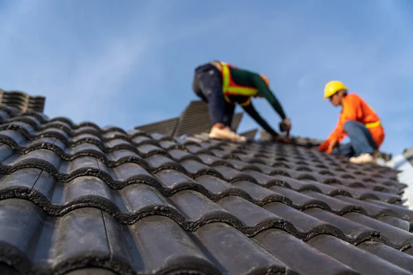 Yeni modern bina inşaatının çatısına Beton Çatı Döşemeleri 'nin montajı için çalışan iki çatı ustası. Beton Çatı Döşemeleri Seçici odak.