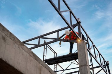 A Welders on risk areas. Steel roof truss welders are working on the roof structure with safety devices to prevent fall safety at the construction site.