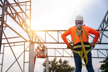 İnşaat alanındaki yükseklikten düşmesini önlemek için güvenlik ekipmanına sahip bir inşaat işçisi.