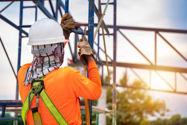 Close up Construction workers are using safety equipment to prevent falls from heights or Fall arrestor device for worker with hooks for safety body harness on the construction site.