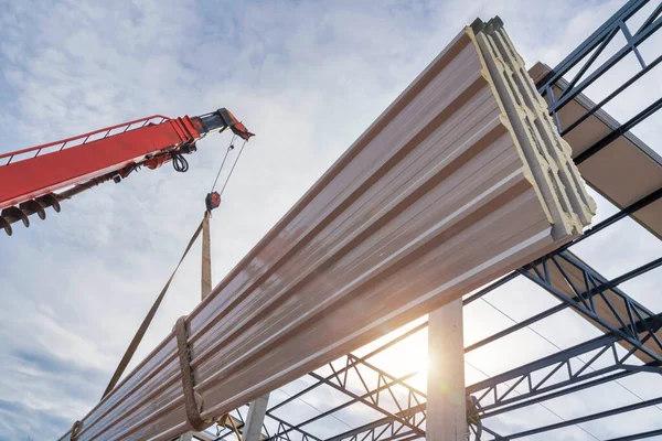 Close up to the PU foam roof sheet with a crane to lift the PU foam roof sheet to install on the steel roof structure at the construction site.