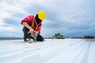 A Roofer working at new roof under construction. Safety body construction, Working at height equipment. Fall arrestor device for worker with hooks for safety body harness on the roof structure