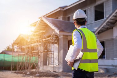 Architect or engineer construction watching unfinished house at outdoors construction site. Building construction collaboration concept.