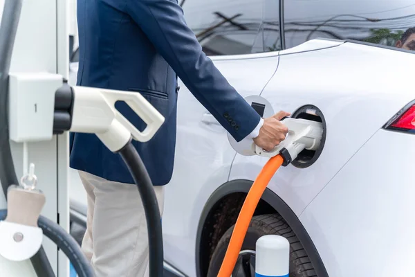 Close-Up hand of A man attaching power cable to electric car. Electric vehicle Recharging battery charging port. Concept of green energy and reduce CO2 emission. EV car.