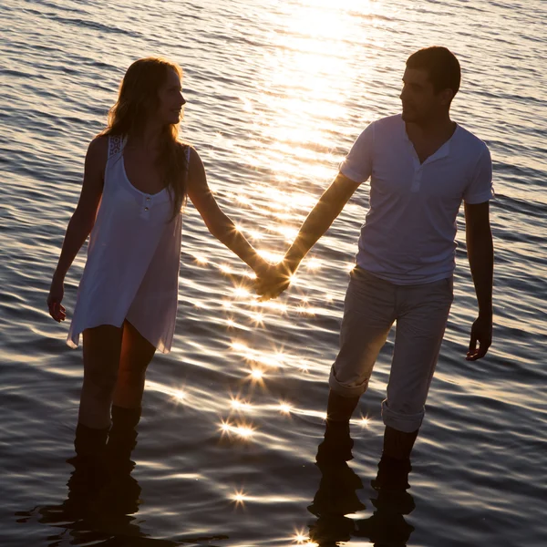 Paar spaziert bei Sonnenuntergang am Meer — Stockfoto