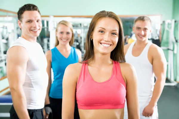 Woman smiling in front of a group of gym people — Stock Photo, Image