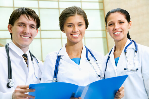 Jeunes médecins debout devant l'hôpital et regardant la caméra — Image Jeunes médecins — Photo