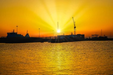 Deniz limanında güneş ışınlarıyla gün batımının altın saatinin göz kamaştırıcı manzarası. Yatay fotoğraf ve seçici odak