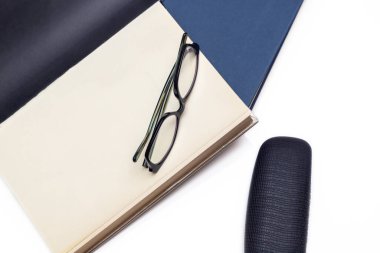 Kapağın yanında ve beyaz arka planda, kitapların üzerinde okuma gözlüğü. Kültür ve eğlence anlayışı. Yatay fotoğraf ve seçici odak 