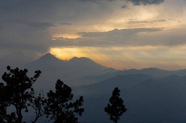 trees in mountains landscape and sunset sky 