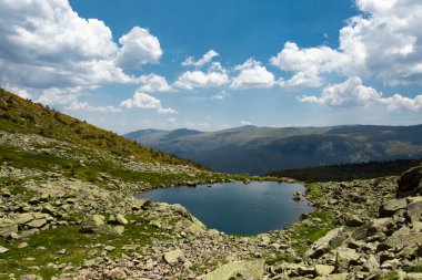 beautiful view on summer mountain fields with pond water, blue sky with clouds 