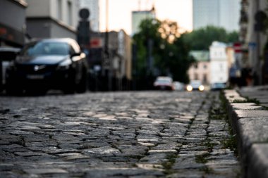 blurred image, pebble road with cars, city architecture, town buildings