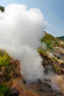 Aktif kraterlerin gaz dumanı püskürdüğü manzaralı dağlar. 