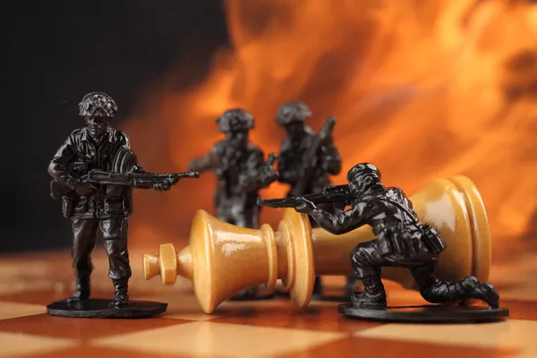 Toy soldiers kill chess King in fire. — Stock Photo, Image