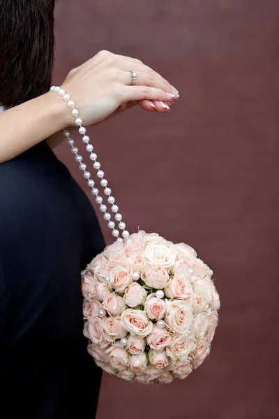 Bukiet róż w kształcie kuli wiszące na rękach panny młodej. — Zdjęcie stockowe