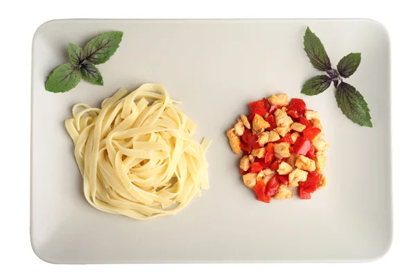 Pasta with grilled chicken and peppers. Chicken Pasta with basil and pepper decorations. Pasta top view. Pasta on a white background.