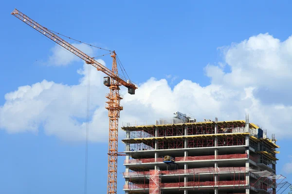 Kran und Gebäude im Bau vor blauem Himmel. — Stockfoto