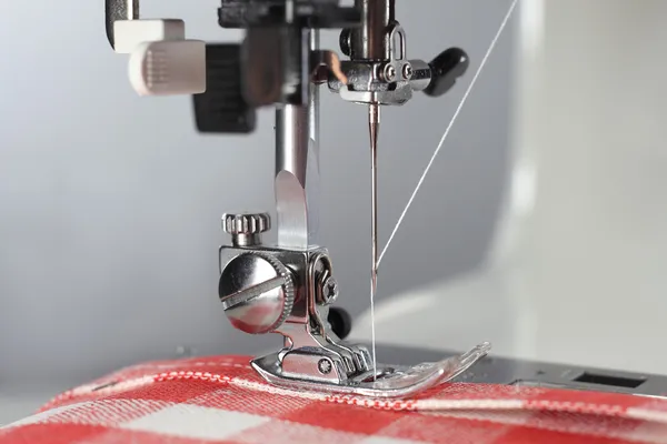 Tailor. Sewing machine working part with linen fabric in the red cell. — Stock Photo, Image