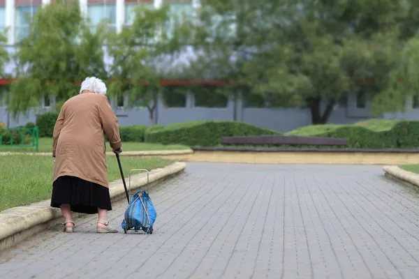 La vejez - no hay alegría. Una anciana con una bolsa vista por detrás. Mujer vieja cansada . — Foto de Stock