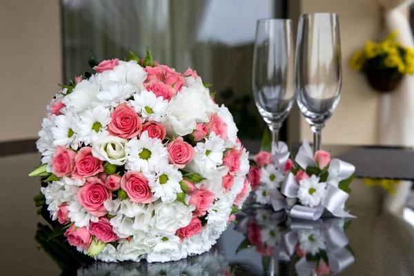 Svatba. Svatební kytice a sklenice na víno na stole poblíž novomanželé domů. — Stock fotografie