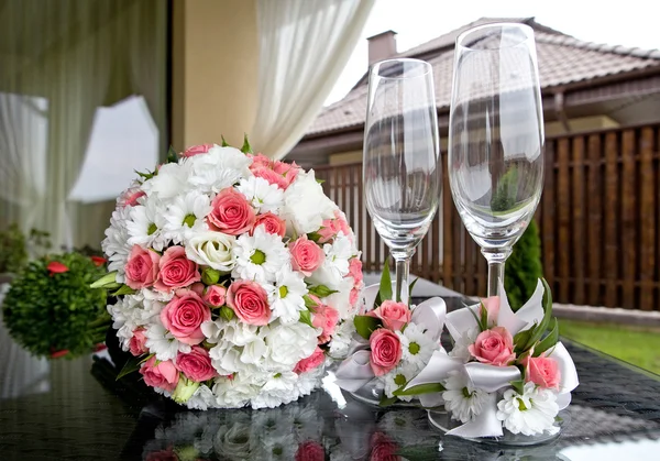 Casamento. Buquê de noiva e copos de vinho em uma mesa . — Fotografia de Stock
