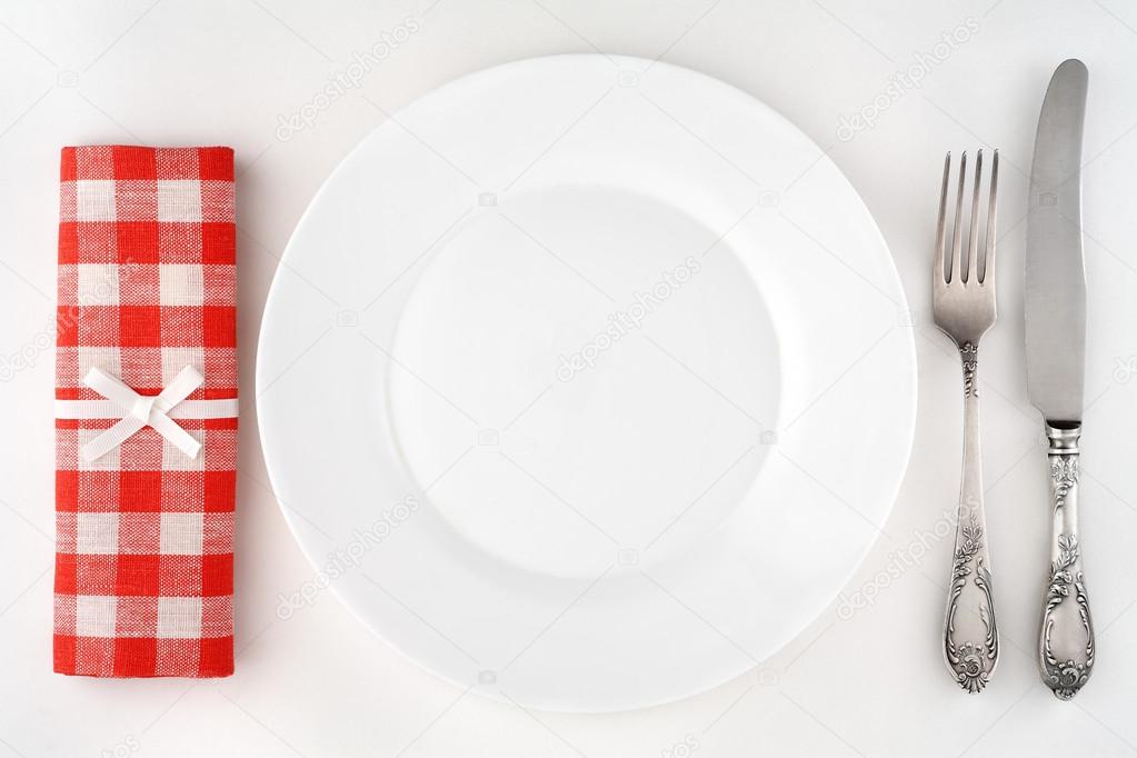 Vintage cutlery set with fork, knife, plate and red checkered napkin. Overhead view.