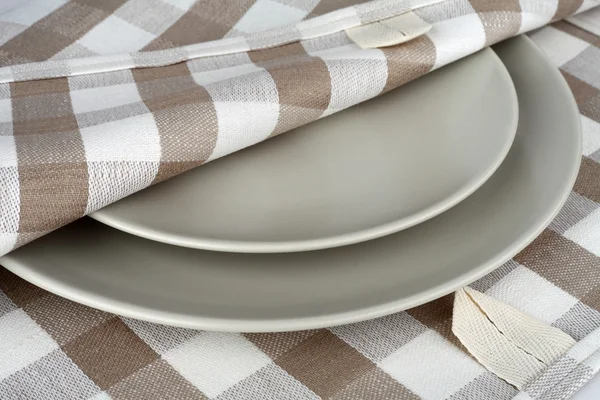 Handtuch in beige karierten und grauen Tellern. Küchentuch und Teller. — Stockfoto