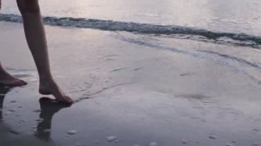 Kasvetli havada kumsalda yürüyen bir kız.