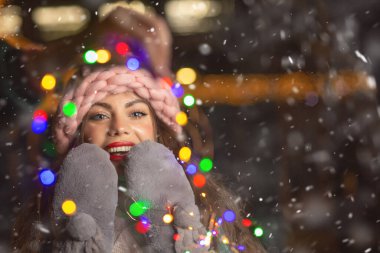Kar yağışı sırasında sokak fuarında yürüyen kırmızı ceketli heyecanlı genç bir kadın. Boş boşluk