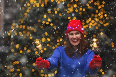 Heyecanlı esmer kadın kar yağarken sokağın ortasında ışıldayan ışıklarla eğleniyor. Metin için boşluk