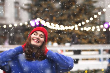 Neşeli esmer kadın, kar yağışı sırasında Noel panayırında eğleniyor. Metin için boşluk