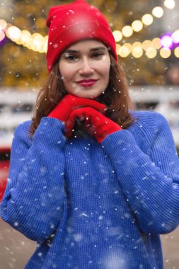 Mutlu esmer kadın, kar yağarken Noel Fuarı 'nda yürüyor.