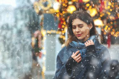 Modaya uygun giyinmiş genç bir kadın kar yağışı sırasında sokakta yürüyor. Boş boşluk