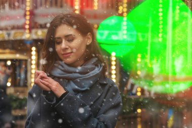 Göz kamaştırıcı kadın kar yağışı sırasında sokakta yürürken gri bir ceket giyiyor. Boş boşluk