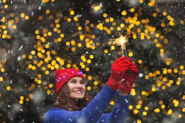 Güzel esmer kadın kar yağarken parlak ışıklarla eğleniyor.
