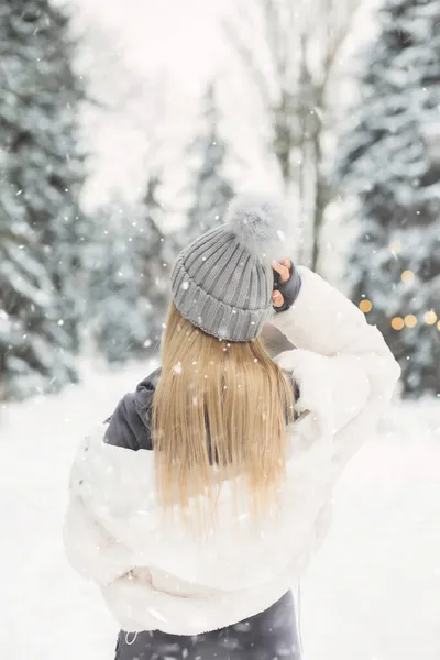 美丽的金发女人穿着白衣 在下雪天望着森林 — 图库照片