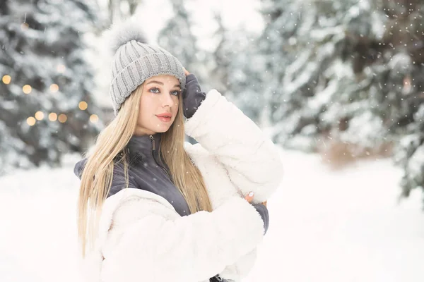 雪の日に森の中を歩く白いコートを着た若いブロンドの女性 テキストのスペース — ストック写真