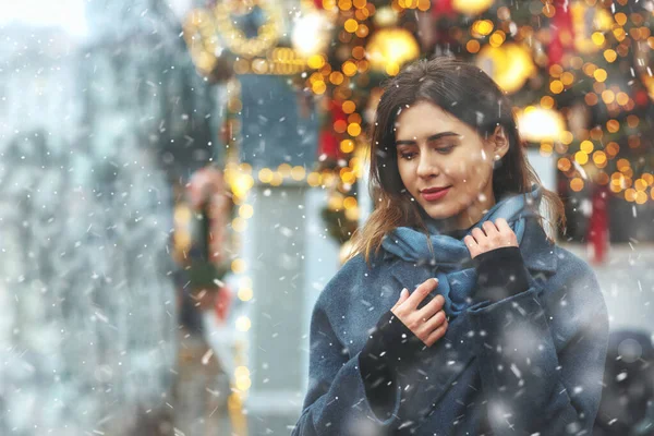Modaya uygun giyinmiş genç bir kadın kar yağışı sırasında sokakta yürüyor. Boş boşluk