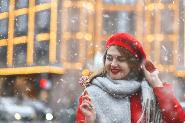 Piękna Młoda Kobieta Czerwonym Płaszczu Trzymająca Słodycze Podczas Opadów Śniegu — Zdjęcie stockowe