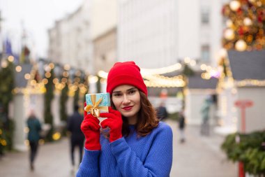 Sevimli genç bayan Noel panayırında bir kutuda hediye alıyor.