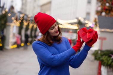 Sevimli genç bir kadın Noel panayırında bir kutuda hediyesini tutuyor.