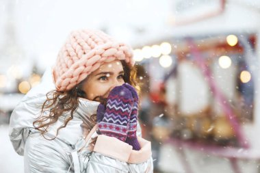 Kar yağarken gülümseyen ve yüzünü kapatan olumlu genç bir kadın. Metin için boşluk