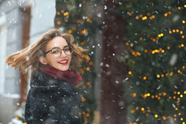 Noel tatilinde kar yağışının keyfini çıkaran neşeli genç bir kadın. Metin için boşluk