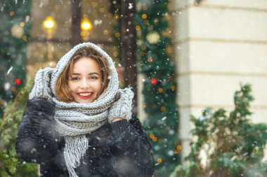Noel tatilinde dekore edilmiş gösterinin yanında kar yağışının keyfini çıkaran pozitif bir genç kadın. Metin için boşluk