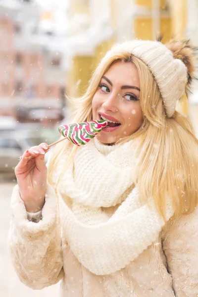 壮大なブロンド女性食べるカラフルなキャンディーで通りに雪の結晶 — ストック写真