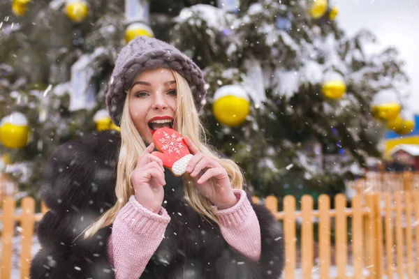 Lovely Blond Woman Wears Knitted Hat Biting Sweet Gingerbread Cookie — Stock Photo, Image