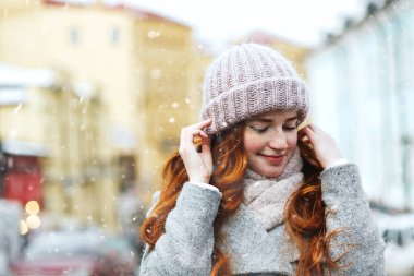 Kar yağışı sırasında eski şehirde yürüyen çekici kızıl saçlı bir kadının sokak portresi. Boş boşluk