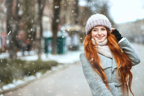 在降雪时 一个红头发的女人穿着外套在城市里散步 案文的篇幅 — 图库照片